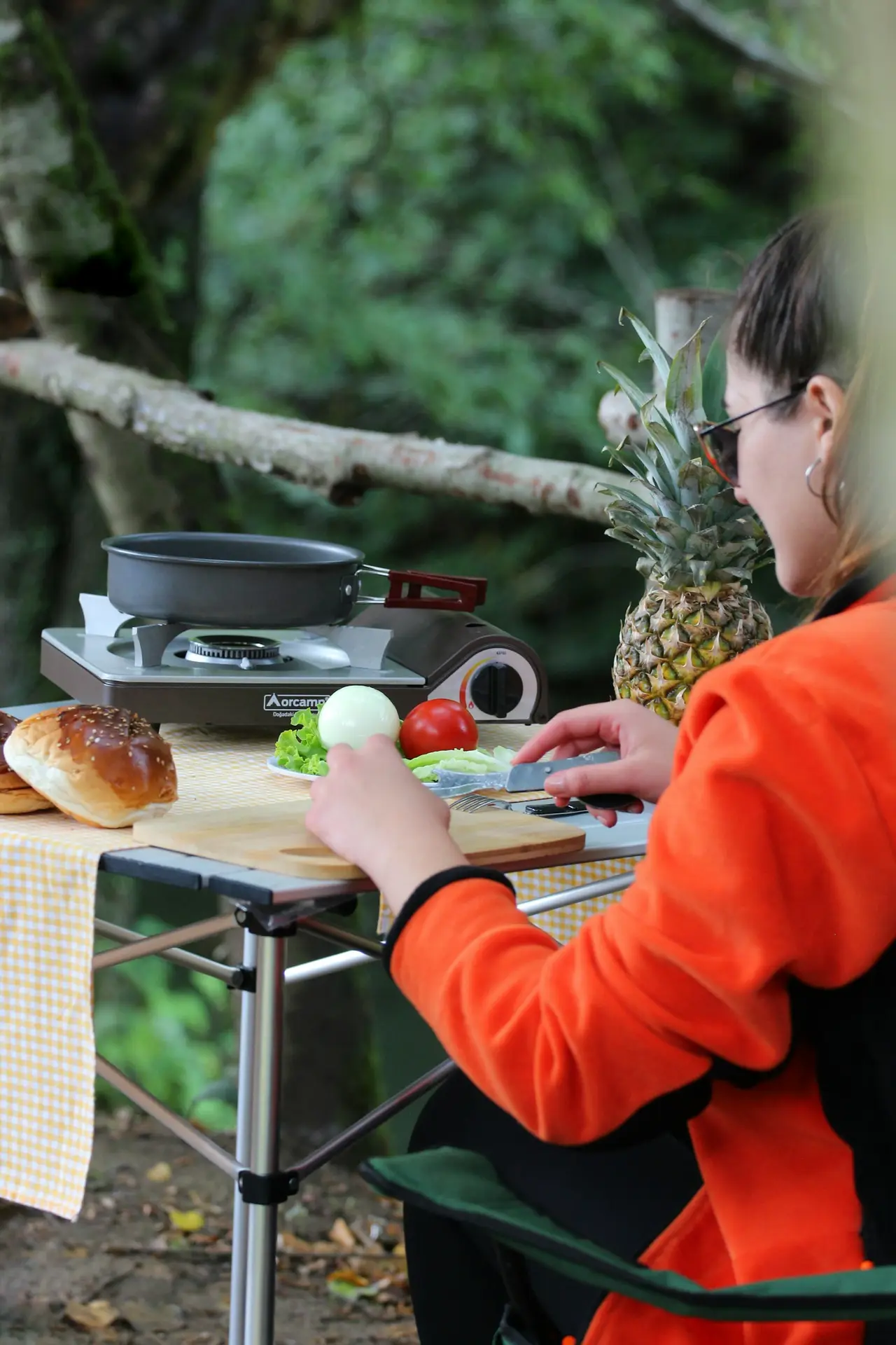 A person sitting at a camp table with a plate of food.