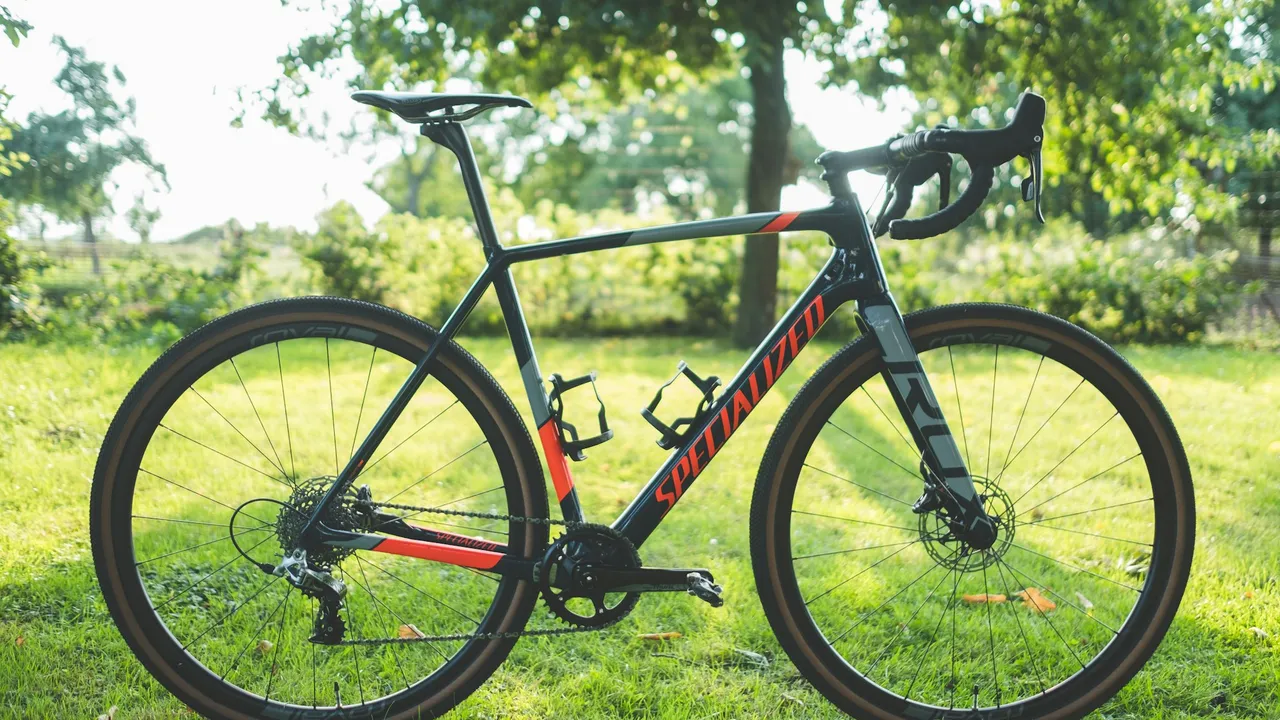 A drop-bar gravel bike photographed side-on against grass, both tyres in full view.