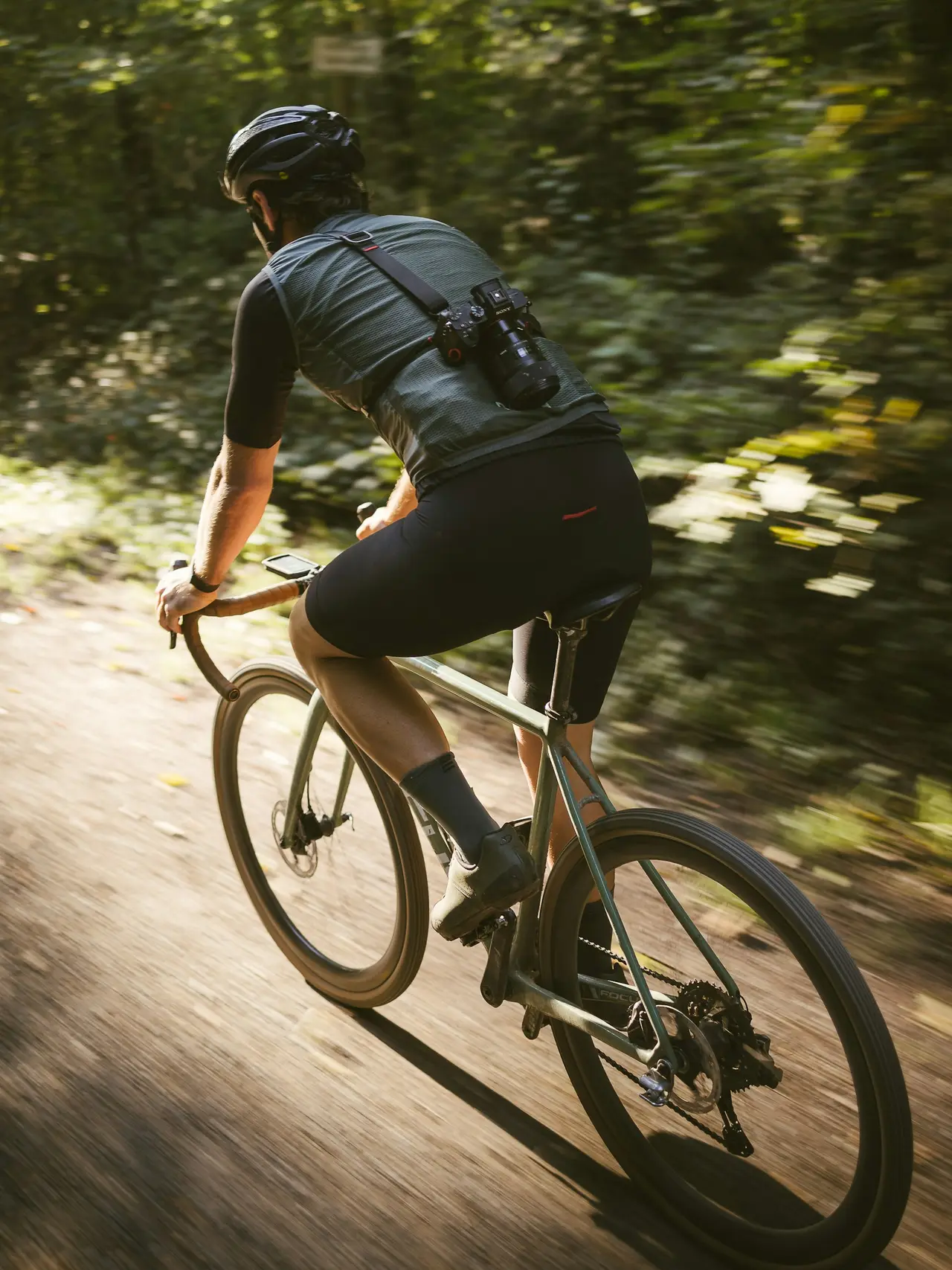 A rider on a drop-bar gravel bike climbing a dry dirt road.