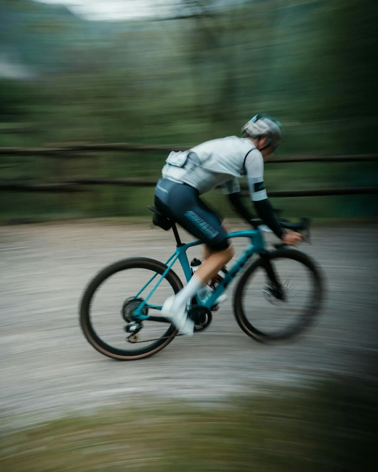A panning shot of a rider on a gravel bike at speed, the background streaked to blur.