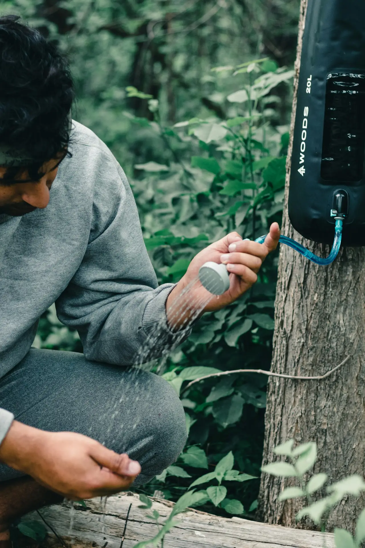 A person sitting on a fallen tree trunk with kit spread beside them.