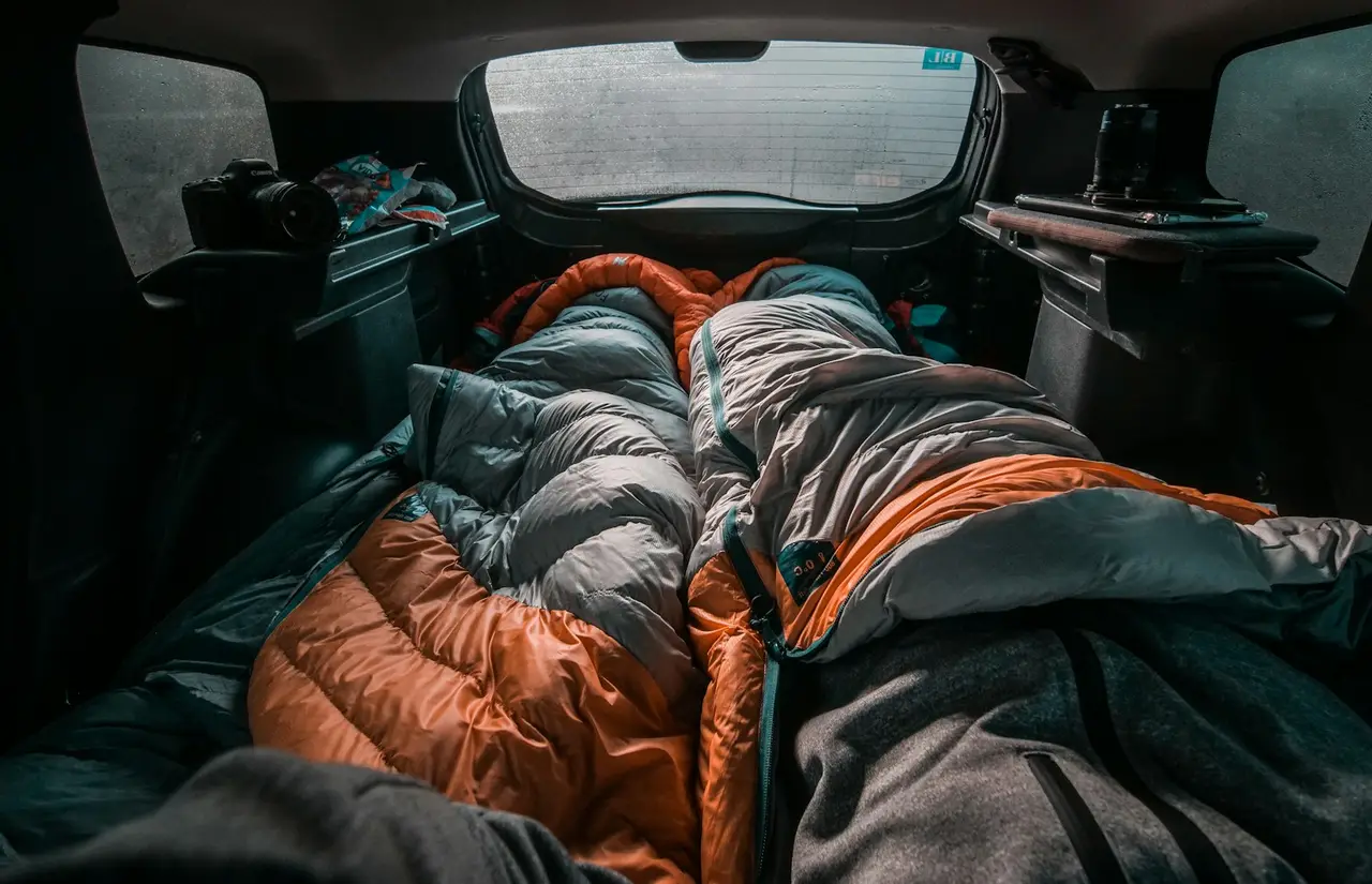 Sleeping bags and quilts lofted up in the back of a vehicle.