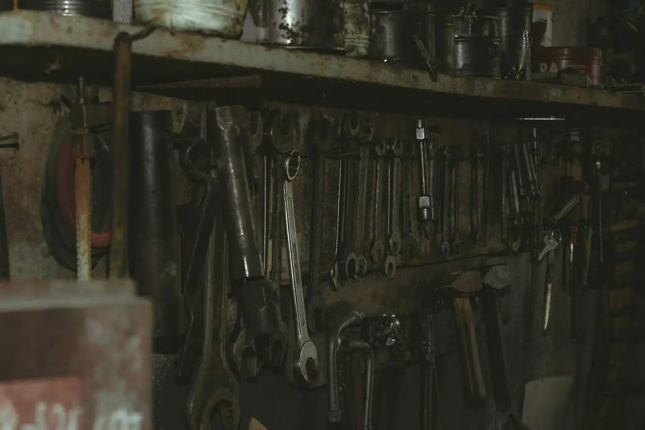 A wall of well-used hand tools hanging in a dim workshop.