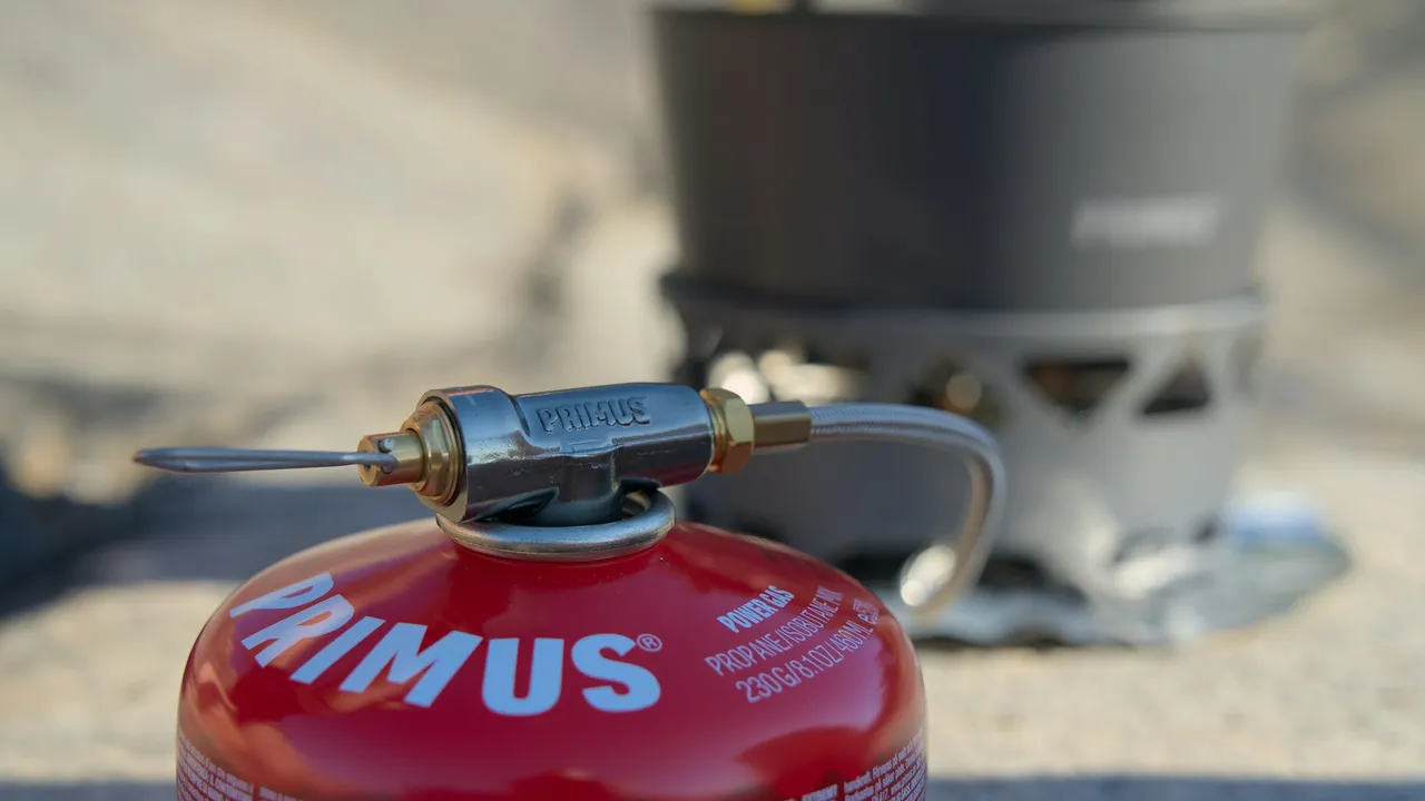 A pot on a burner screwed to a gas canister, photographed at ground level.