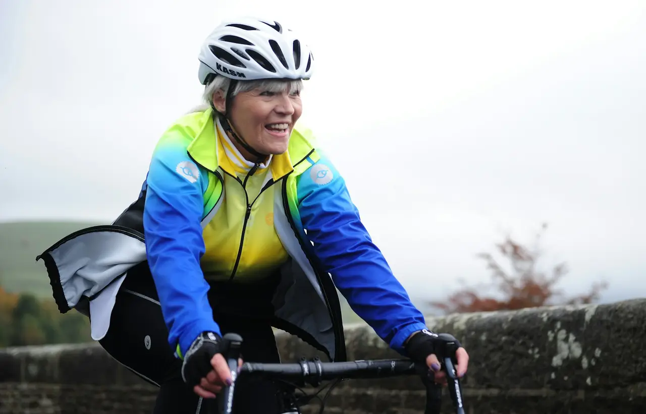 A rider in a bright waterproof jacket riding in grey, wet conditions.