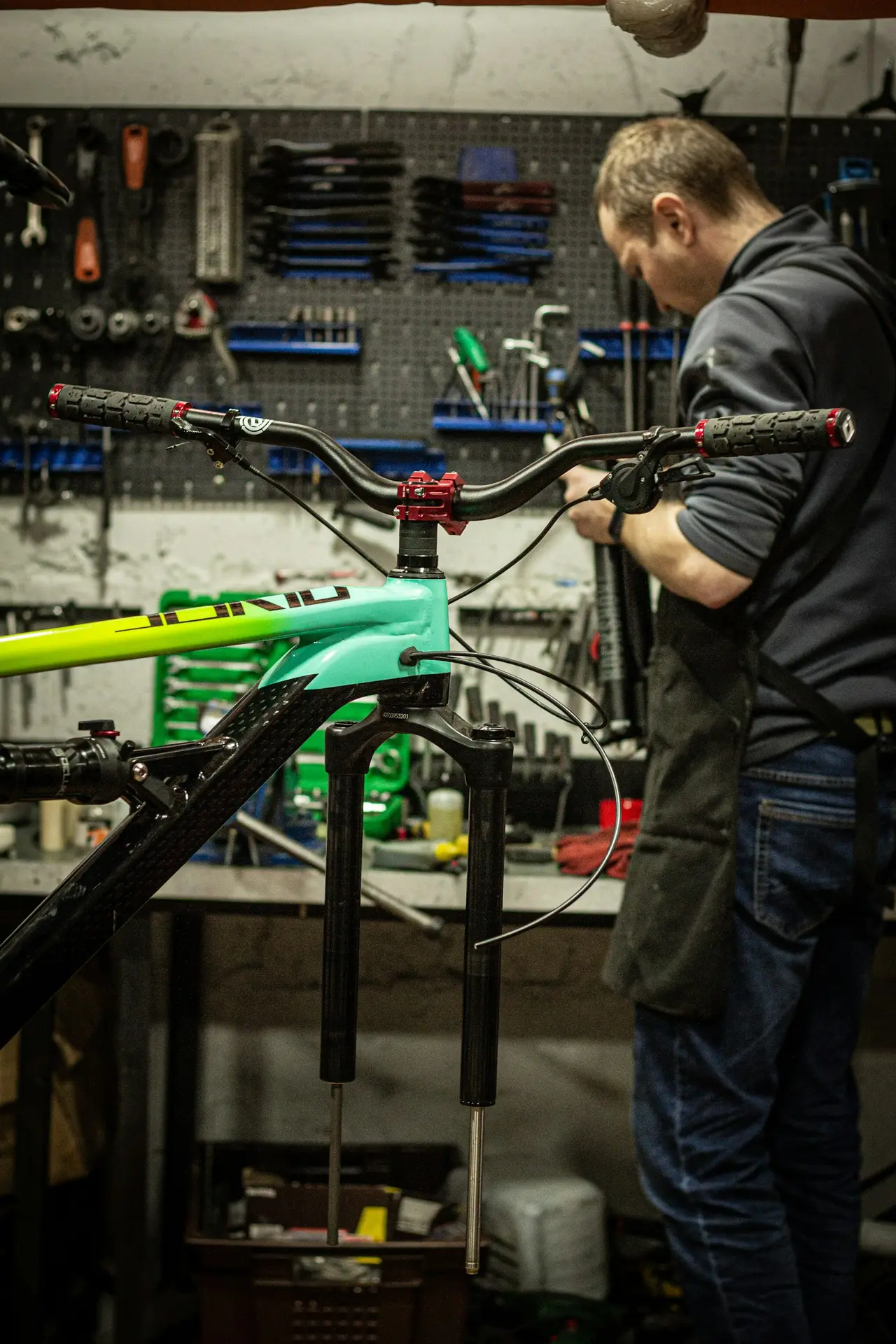 A mechanic working on a bicycle held in a stand in a workshop.